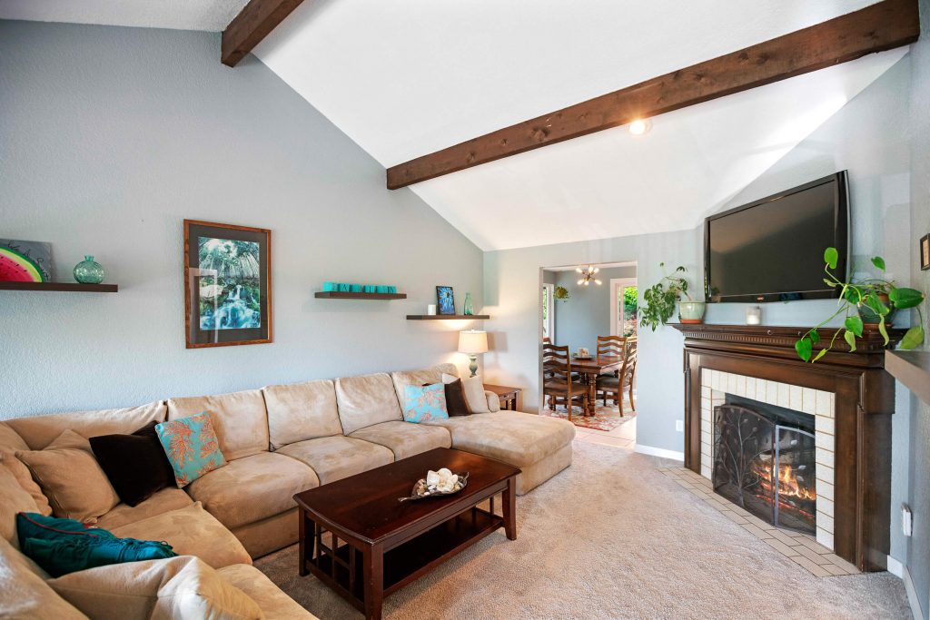 The spacious living room upstairs features vaulted ceilings with wood beams, a beautiful wood-burning fireplace and lots of room to relax.