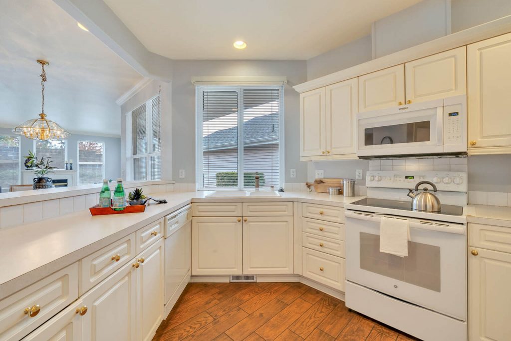 The kitchen features abundant cabinetry, all-white appliances and a huge picture window.