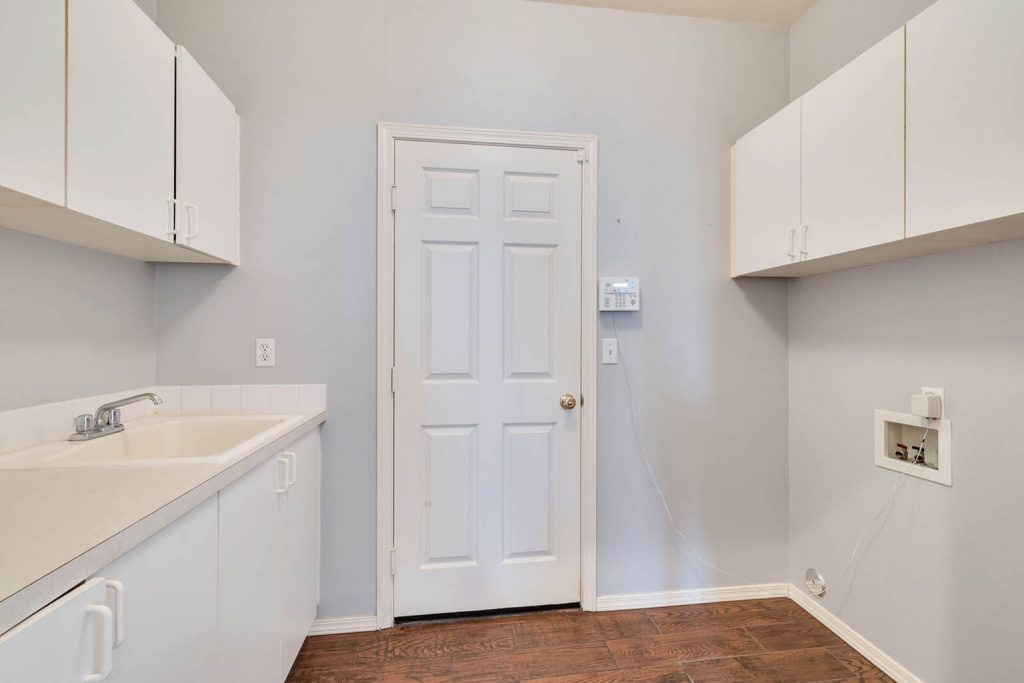 This practical utility room boasts plentiful cabinetry and a utility sink.