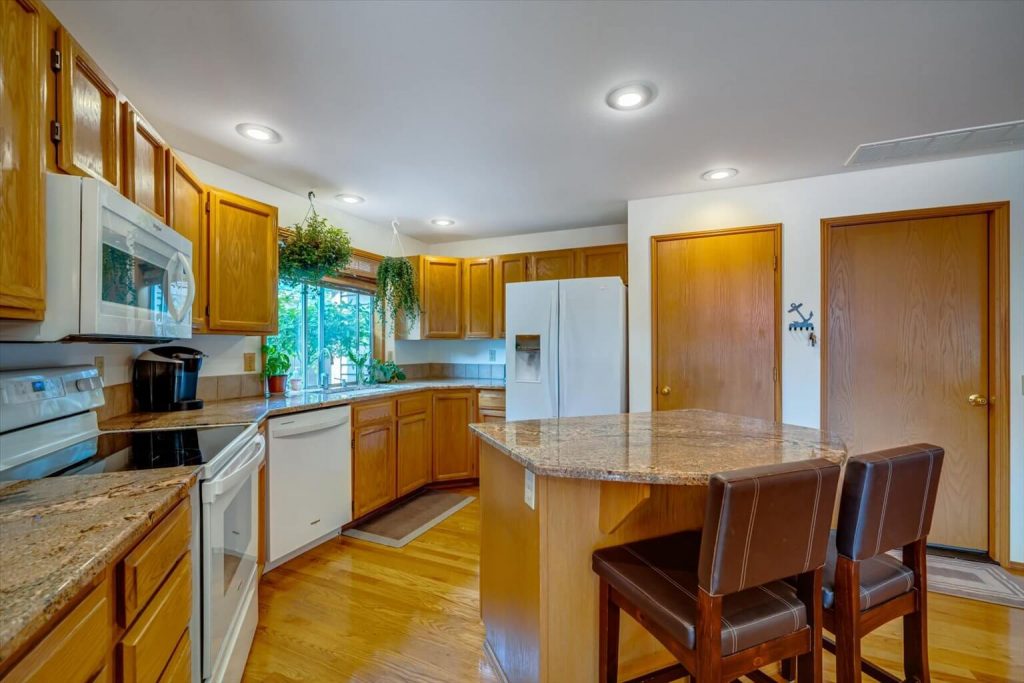 The kitchen features beautiful granite countertops, updated white-on-white appliances, a handy breakfast bar and plenty of cabinetry. The door on the far right leads to an oversized 2-car garage. The door on the left is the pantry.